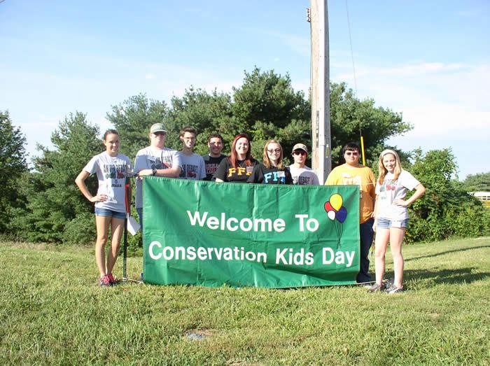 Student volunteers holding a sign "Welcome to Conservation Kids Day"