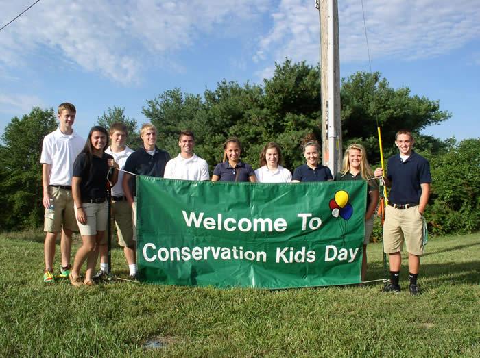 Student volunteers holding a sign "Welcome to Conservation Kids Day"