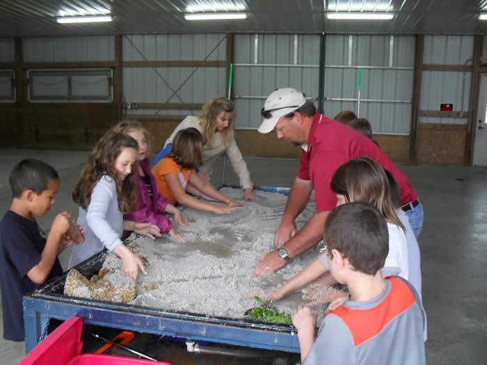 Kids around the stream table that teaches them about water erosion.